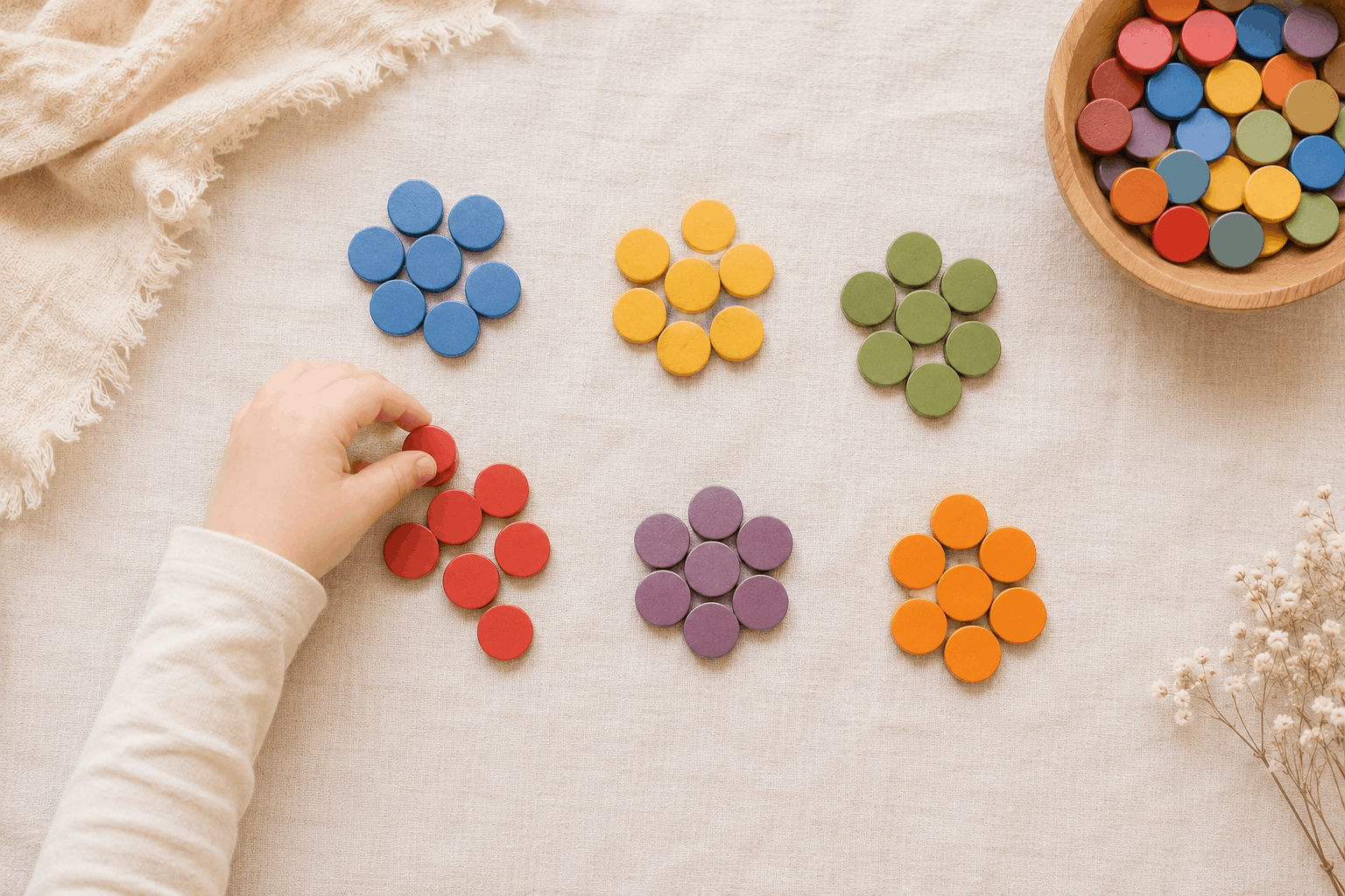 Kinderhand sortiert bunte Knöpfe nach Farben – Konzentration fördern durch Sortieren und Muster legen