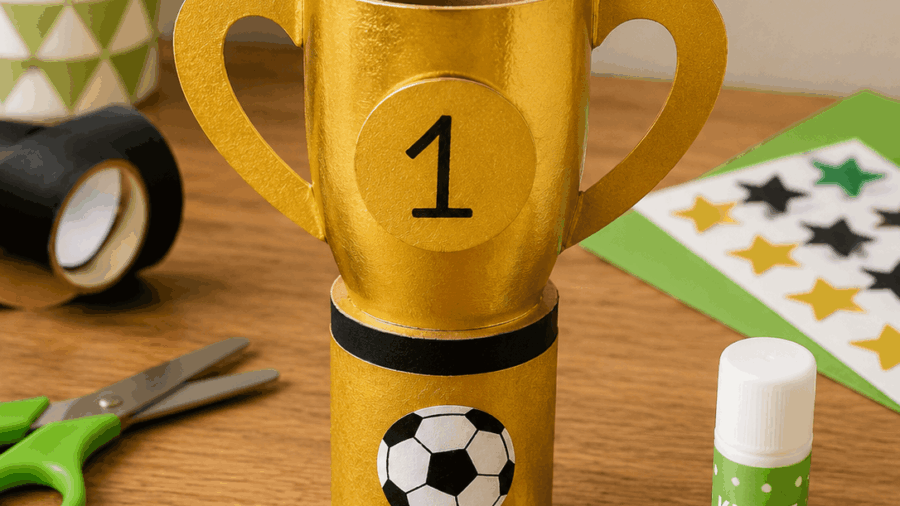 Kleiner selbstgebastelter Pokal aus Goldpapier und Papprolle – Fußball basteln mit Kindern